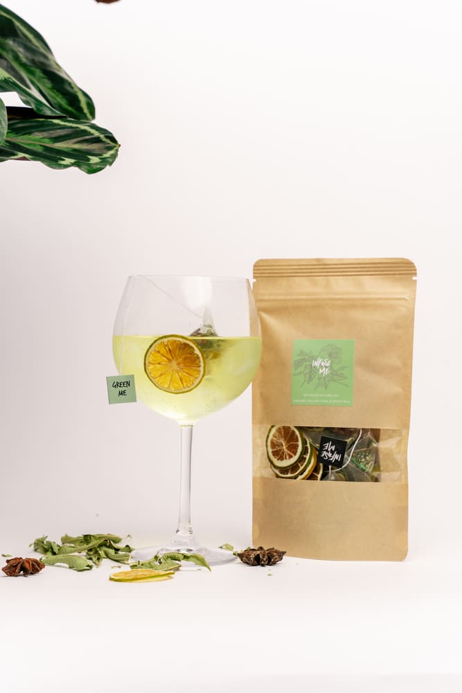 Un cocktail de gin tonic infusé avec Green Me à côté de sa pochette